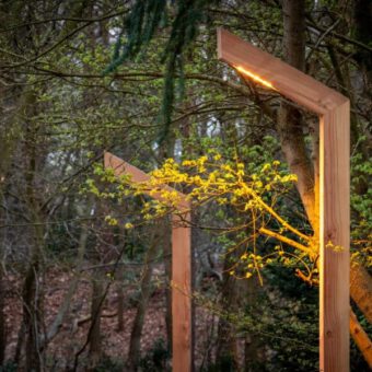 Lampstolpe av trä med utskjutande stolpe i ett hörn av skogen